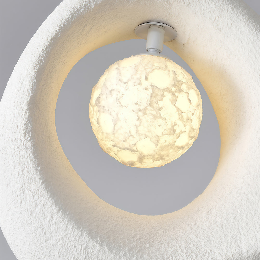 Close-up view of statement pendant light showing fine surface texture and glowing orb detail.