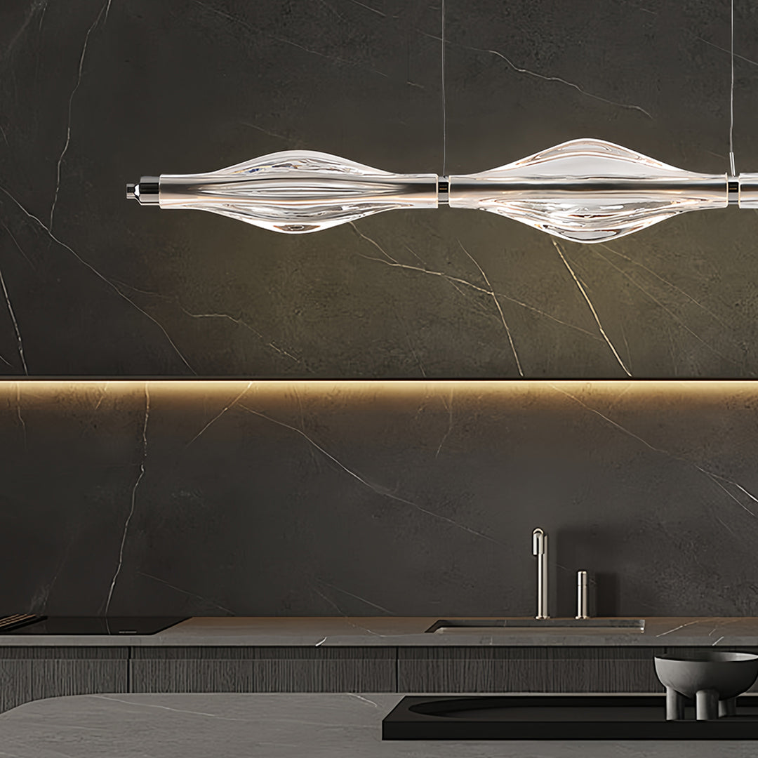 Contemporary crystal pendant lights for kitchen island with a curved design, hanging above a kitchen workspace.
