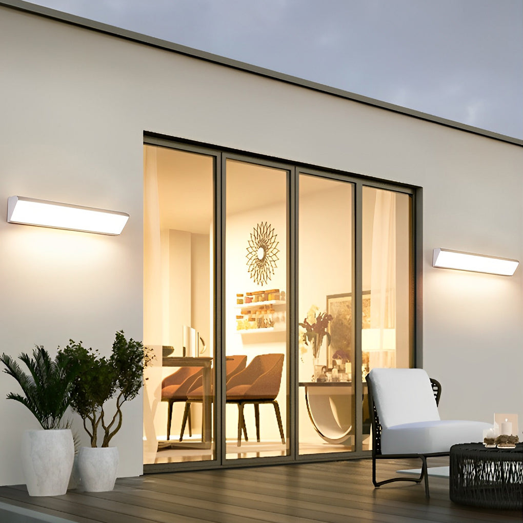 Contemporary exterior wall light illuminating a modern patio and glass doors.