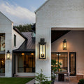 Black external wall light illuminating a contemporary house exterior, enhancing architectural details with warm light.