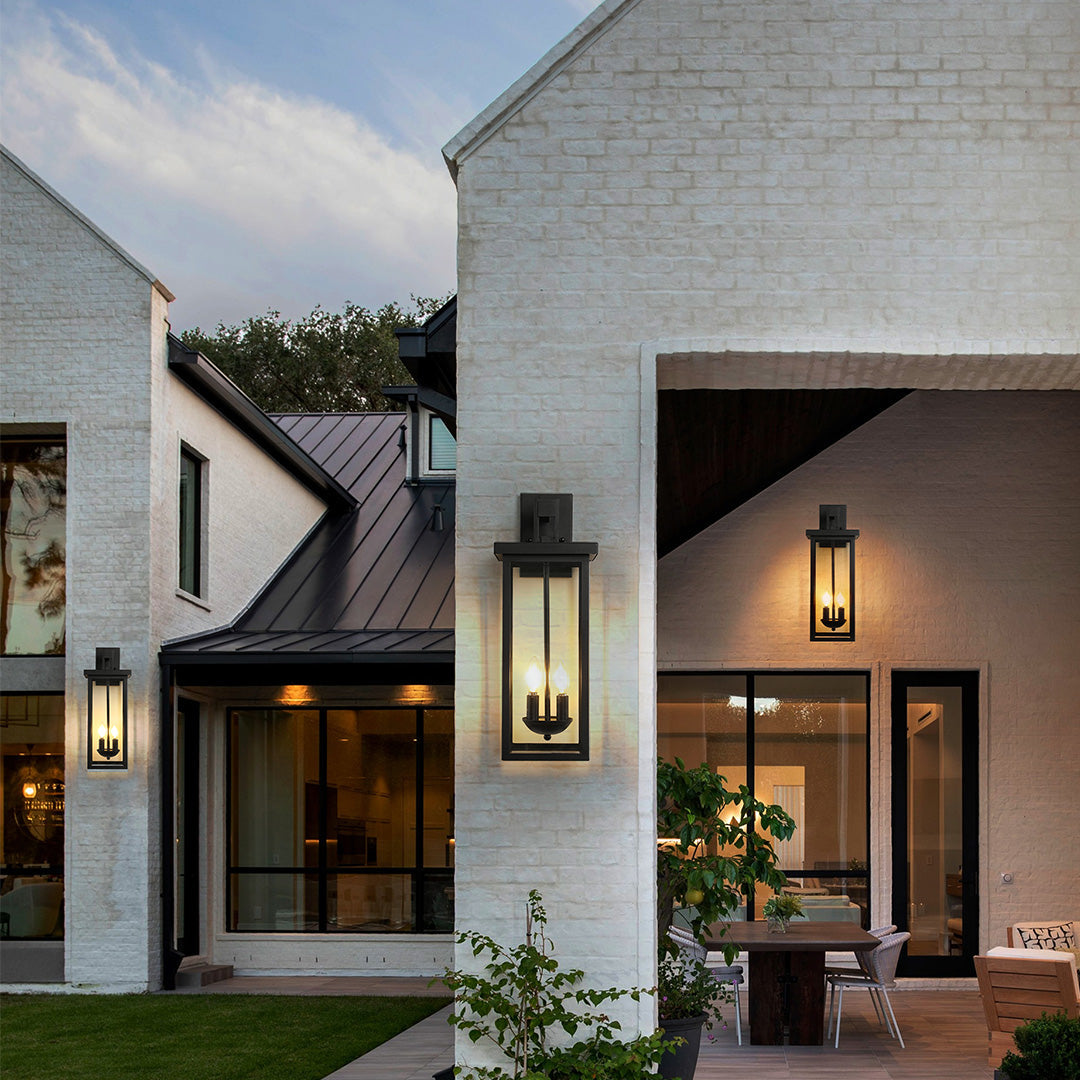 Black external wall light illuminating a contemporary house exterior, enhancing architectural details with warm light.