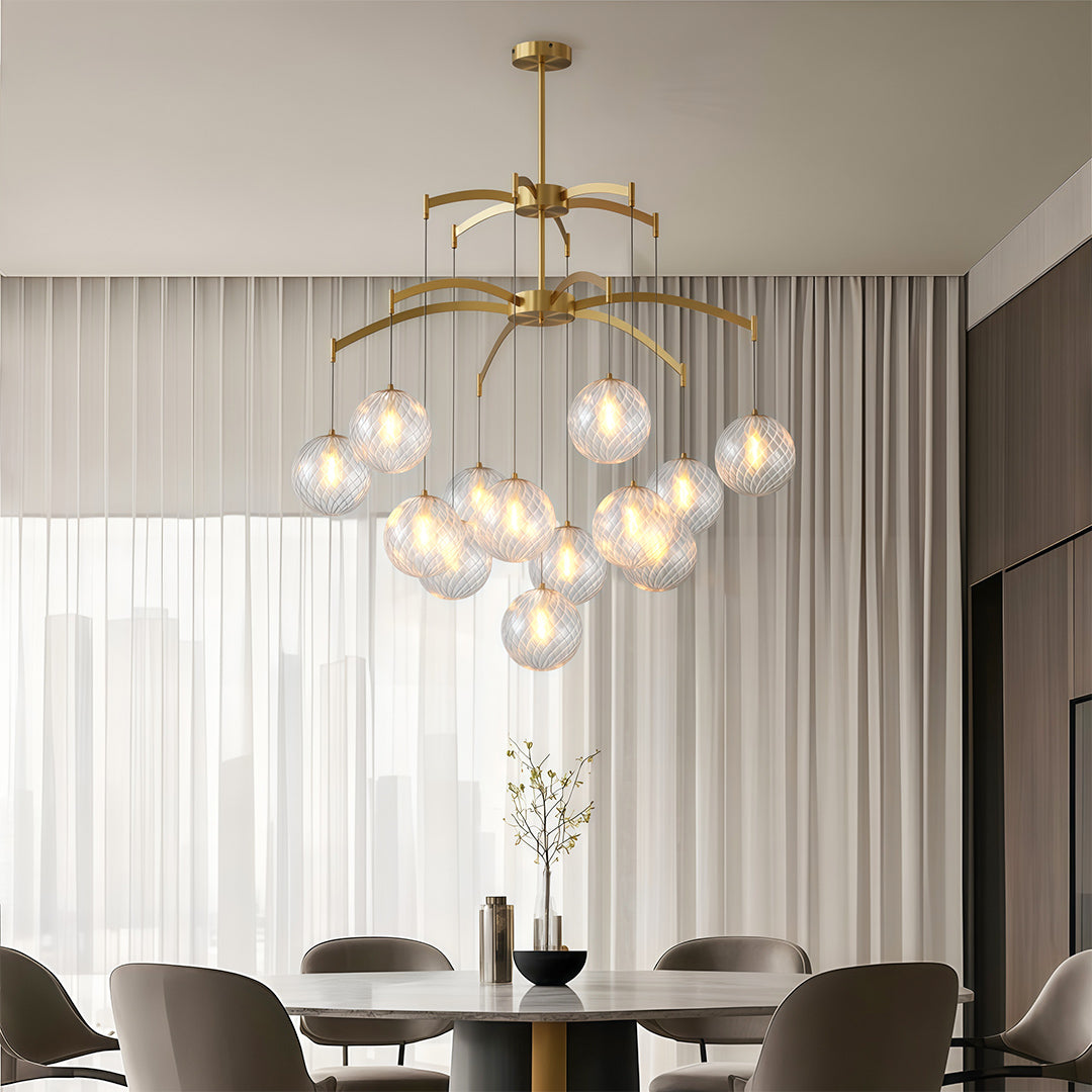 Contemporary modern glass ball chandelier with a gold frame, hanging above a dining table in a stylish home.