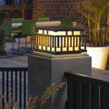 Contemporary outdoor wall lighting pillar mounted light with modern lantern style cage and warm ambient illumination