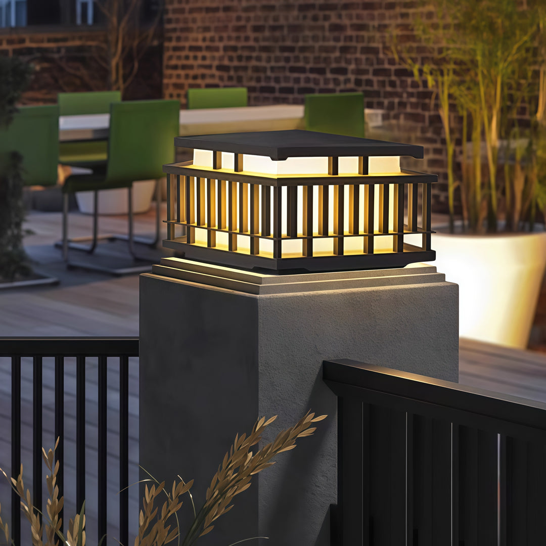 Contemporary outdoor wall lighting pillar mounted light with modern lantern style cage and warm ambient illumination