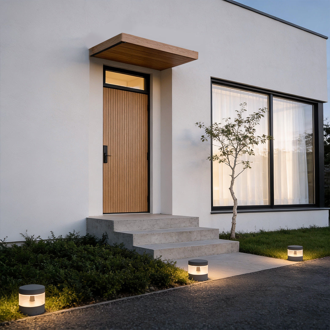 Contemporary path lights used near a modern home entrance, adding subtle illumination to steps and surrounding greenery.