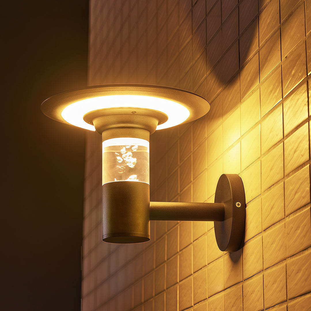 Contemporary solar outdoor wall lighting design projecting a warm, circular light pattern on a tiled exterior wall.