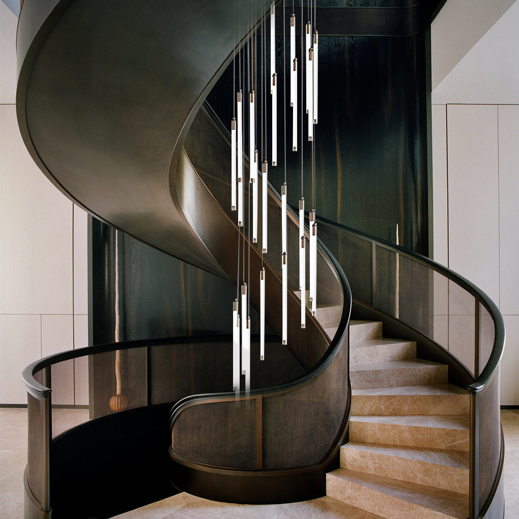 Contemporary staircase chandelier with cascading lights, highlighting a concrete spiral staircase.
