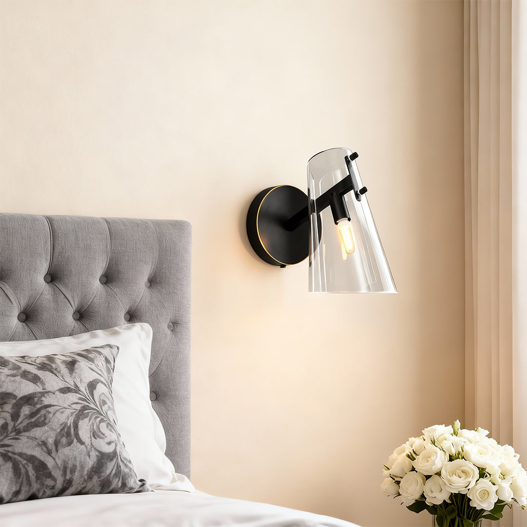 Contemporary wall sconce lighting providing bedside illumination in bedroom with tufted headboard.