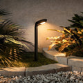 Curved bollard light illuminating garden plants along a landscape edge.