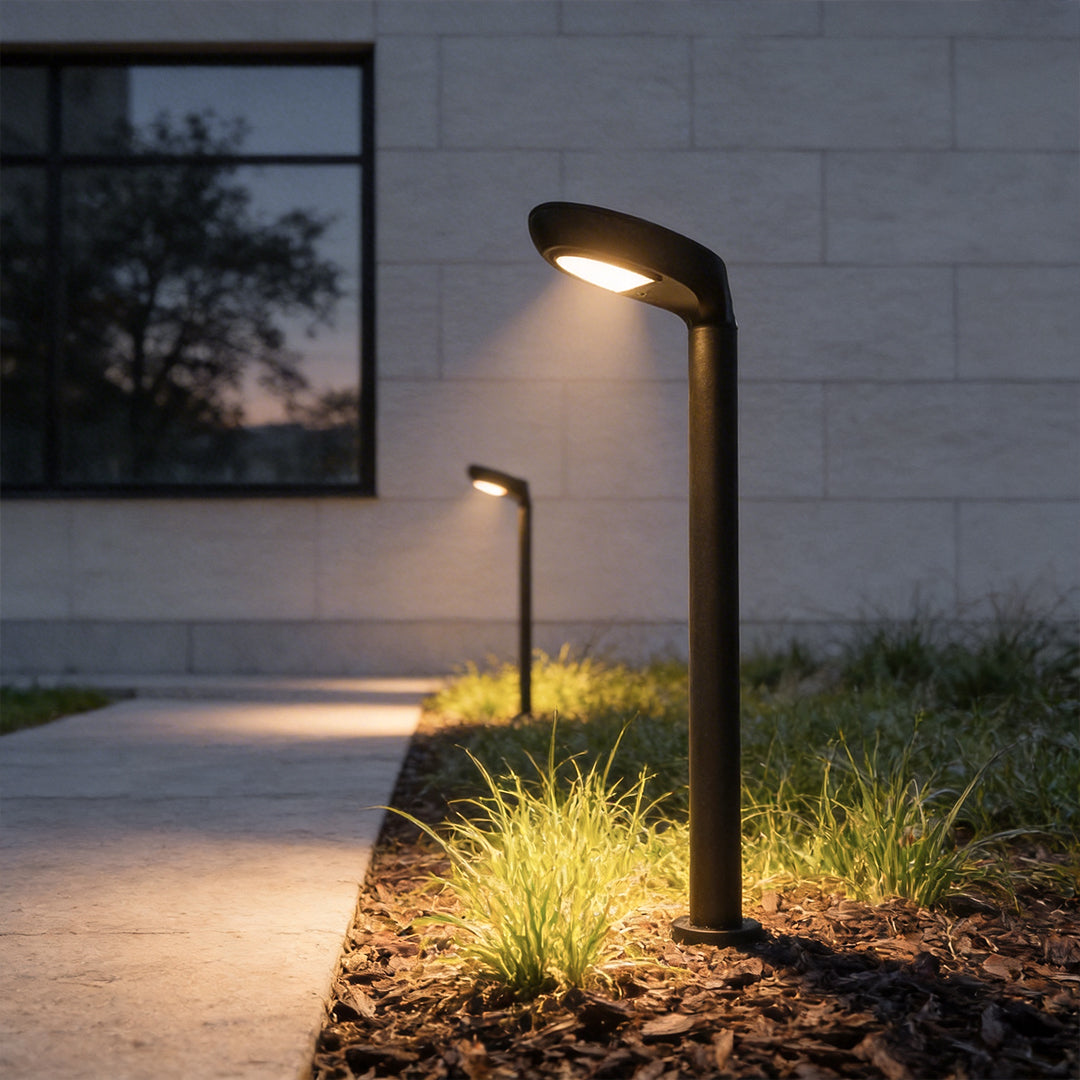 Curved bollard light installed beside a modern building walkway at night.
