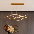 Modern curved LED pendant light with flowing wave design above a minimalist dining table.
