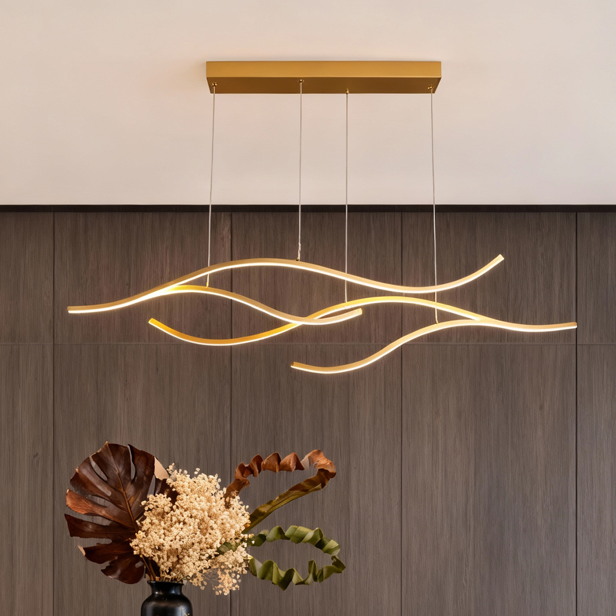 Modern curved LED pendant light with flowing wave design above a minimalist dining table.