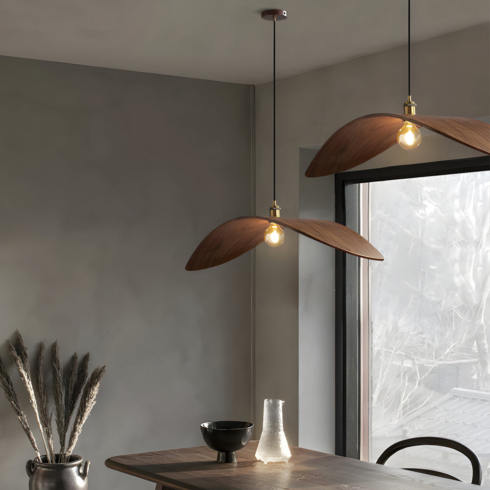 Curved wood pendant light with a sleek design, hanging above a minimalist dining area.