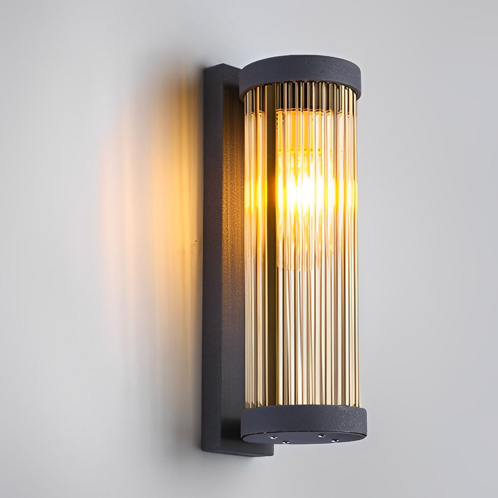 Studio view of cylindrical outdoor wall mount lights featuring a matte black finish and ribbed glass shade on a white wall.