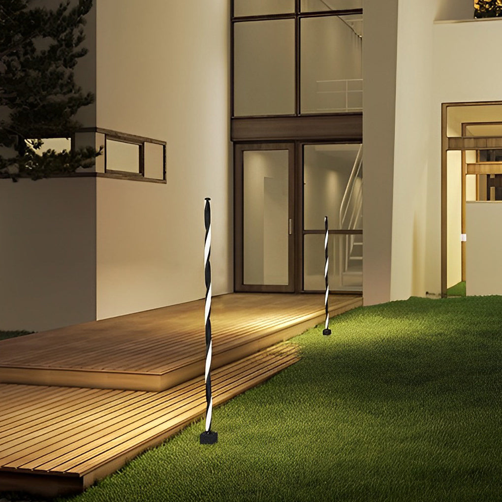 Decorative garden lighting positioned beside a wooden deck and lawn area at night.