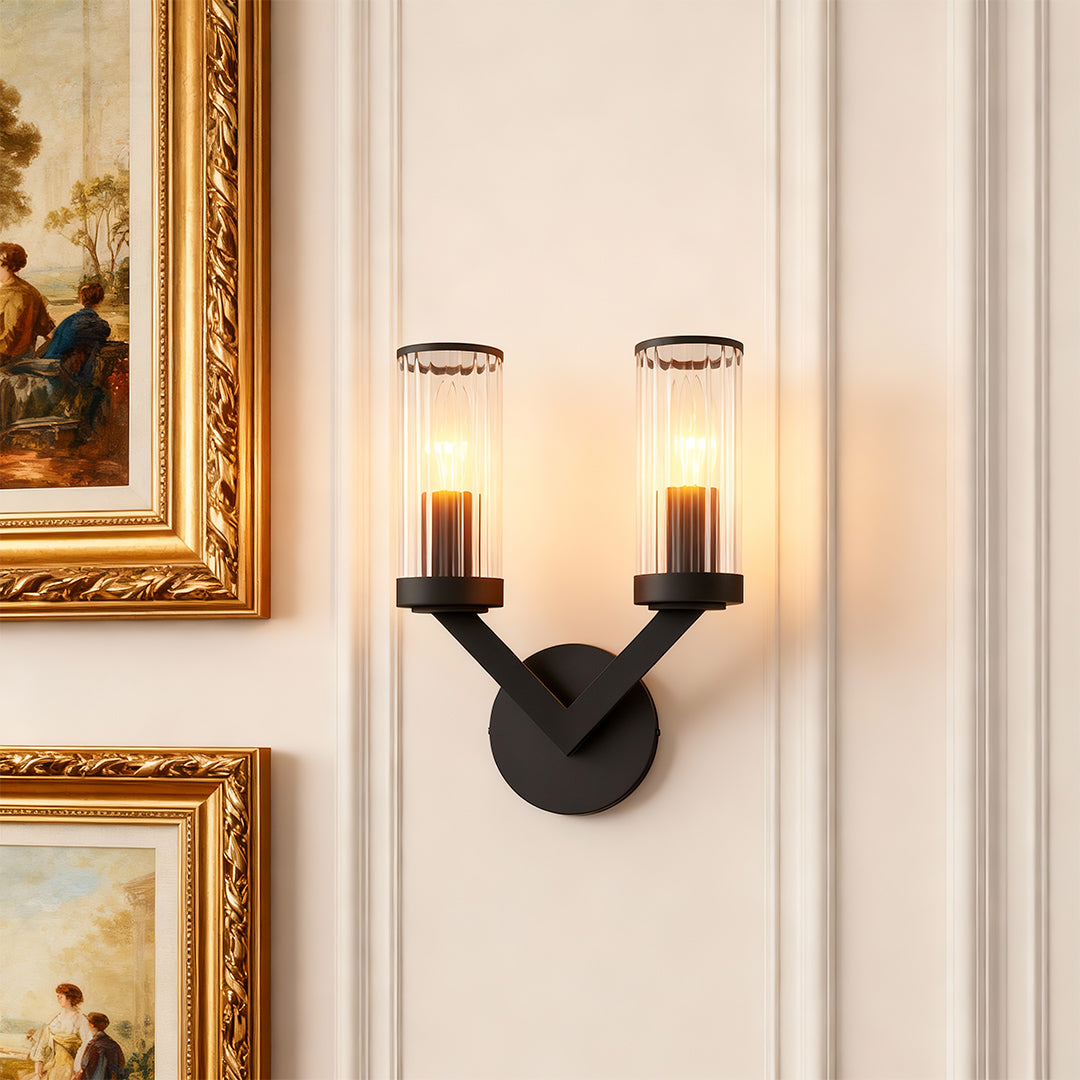 Double sconce wall light providing elegant lighting beside ornate gold-framed mirror.