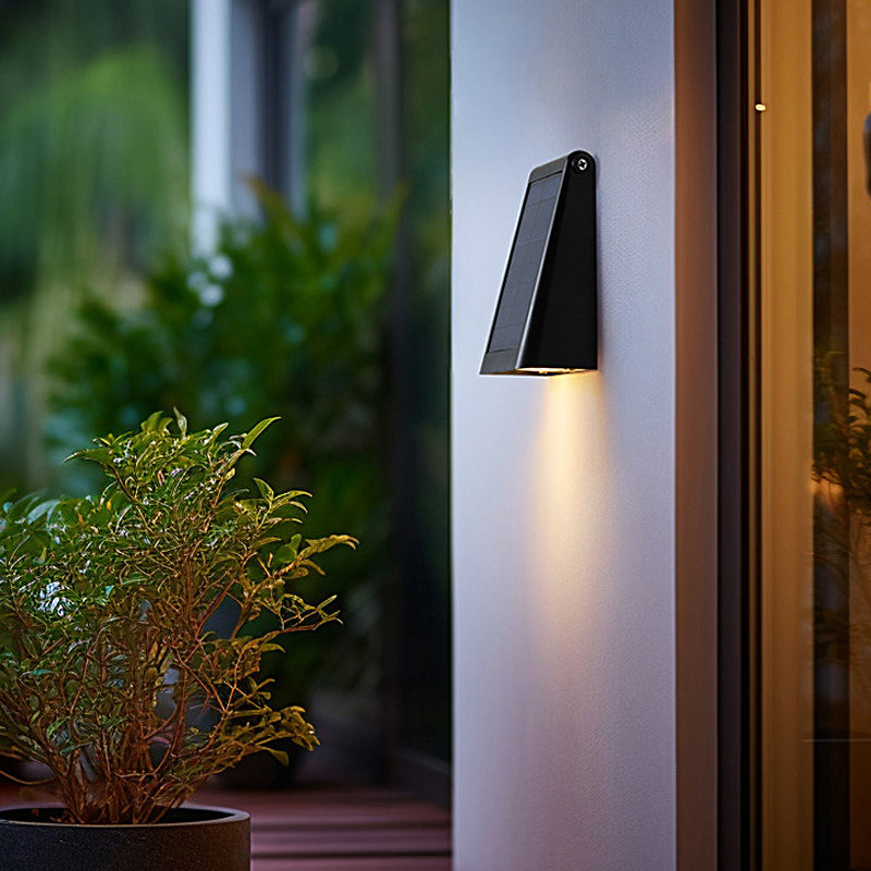 Down light wall sconce installed on a patio wall near plants.