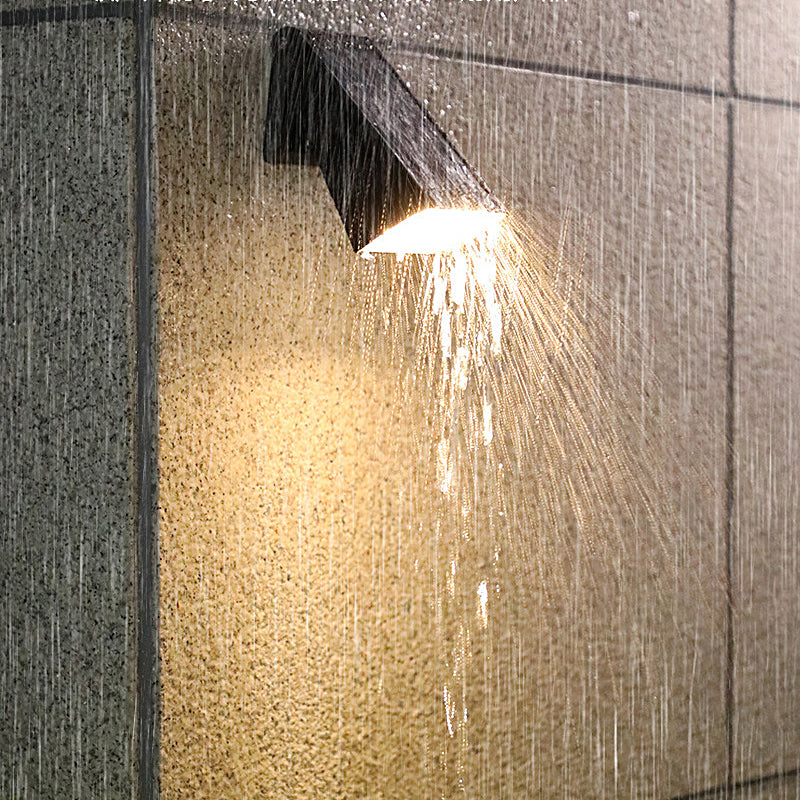 Down light wall sconce operating under rain to demonstrate waterproof design.
