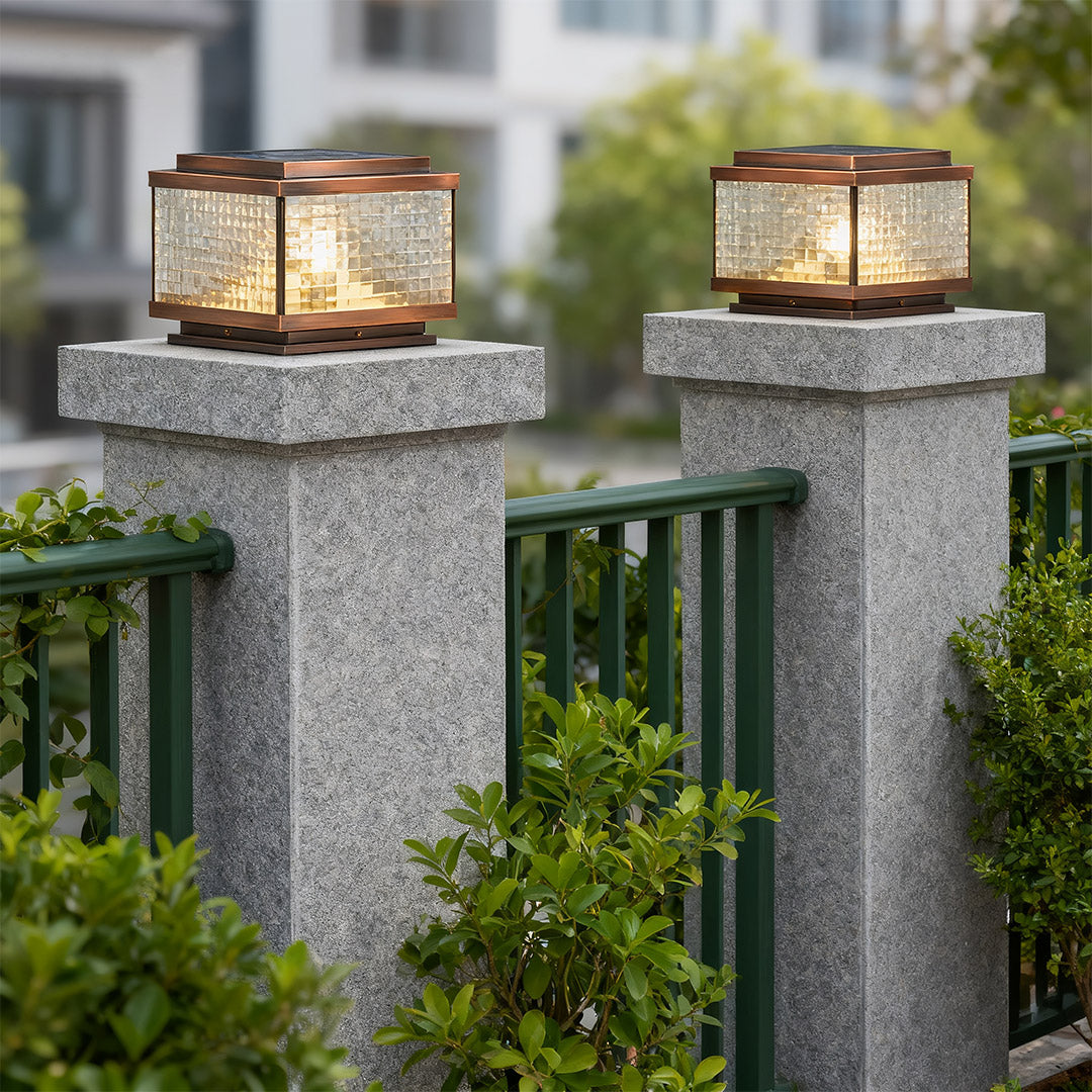 Pair of pillar cap lights on granite posts flanking modern driveway with residential landscaping.