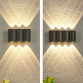 Up and down outdoor wall lights with dual warm spotlights mounted on textured white exterior wall.