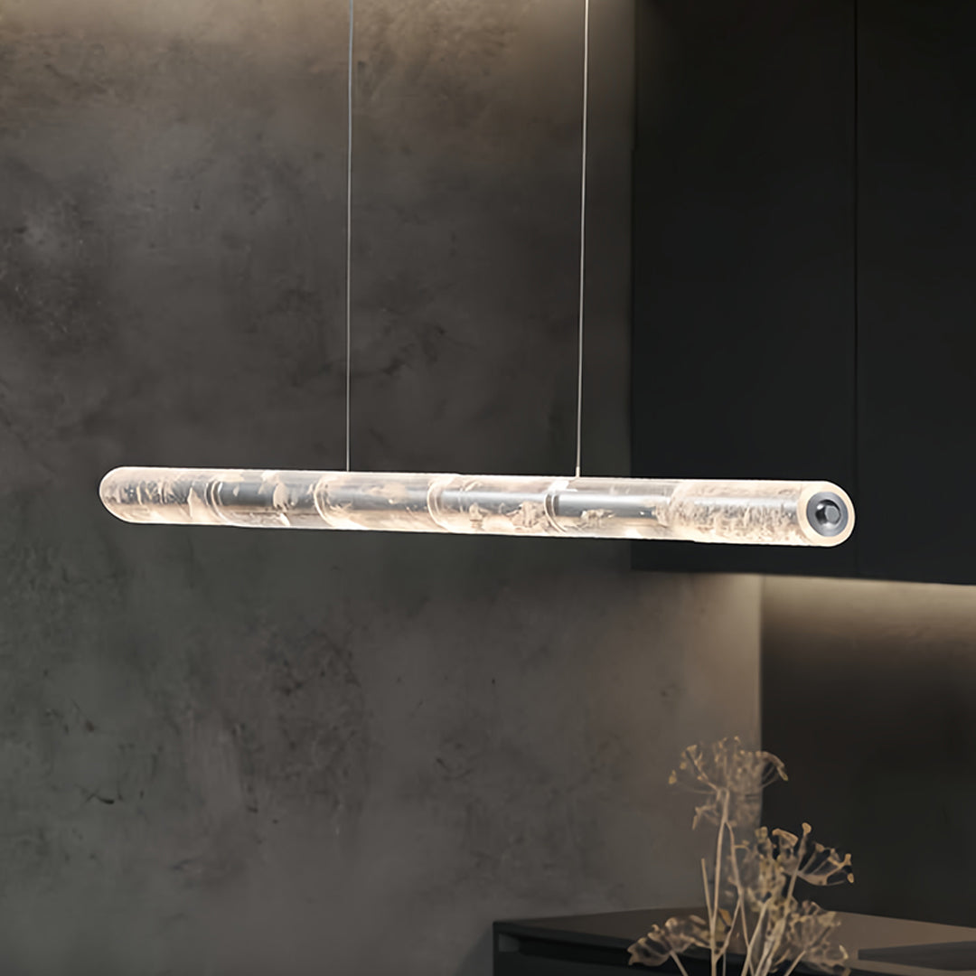Elegant crystal light pendants with a transparent cylindrical design, illuminating a modern dining area.