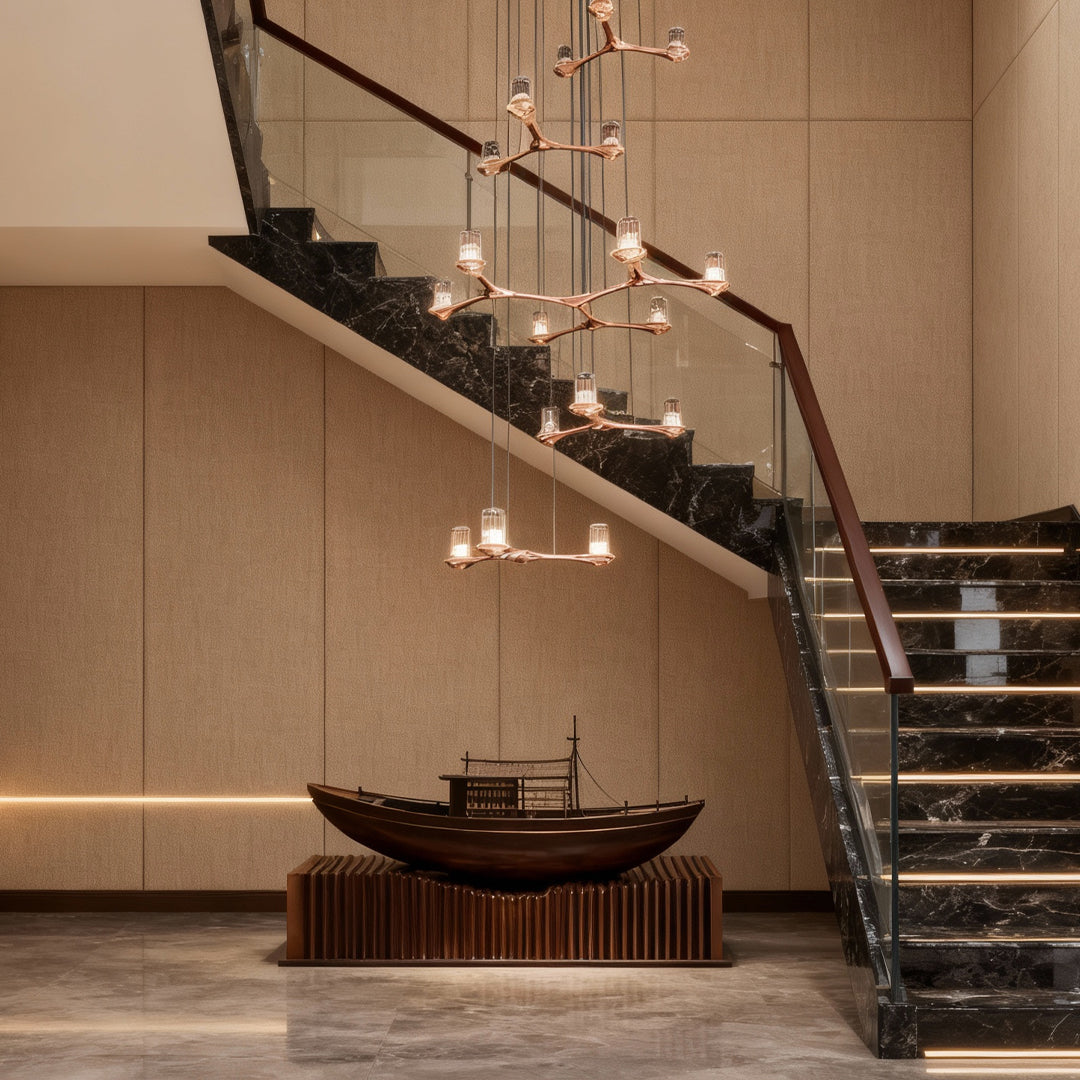 Elegant crystal staircase chandelier cascading alongside curved staircase in sophisticated neutral-toned interior space