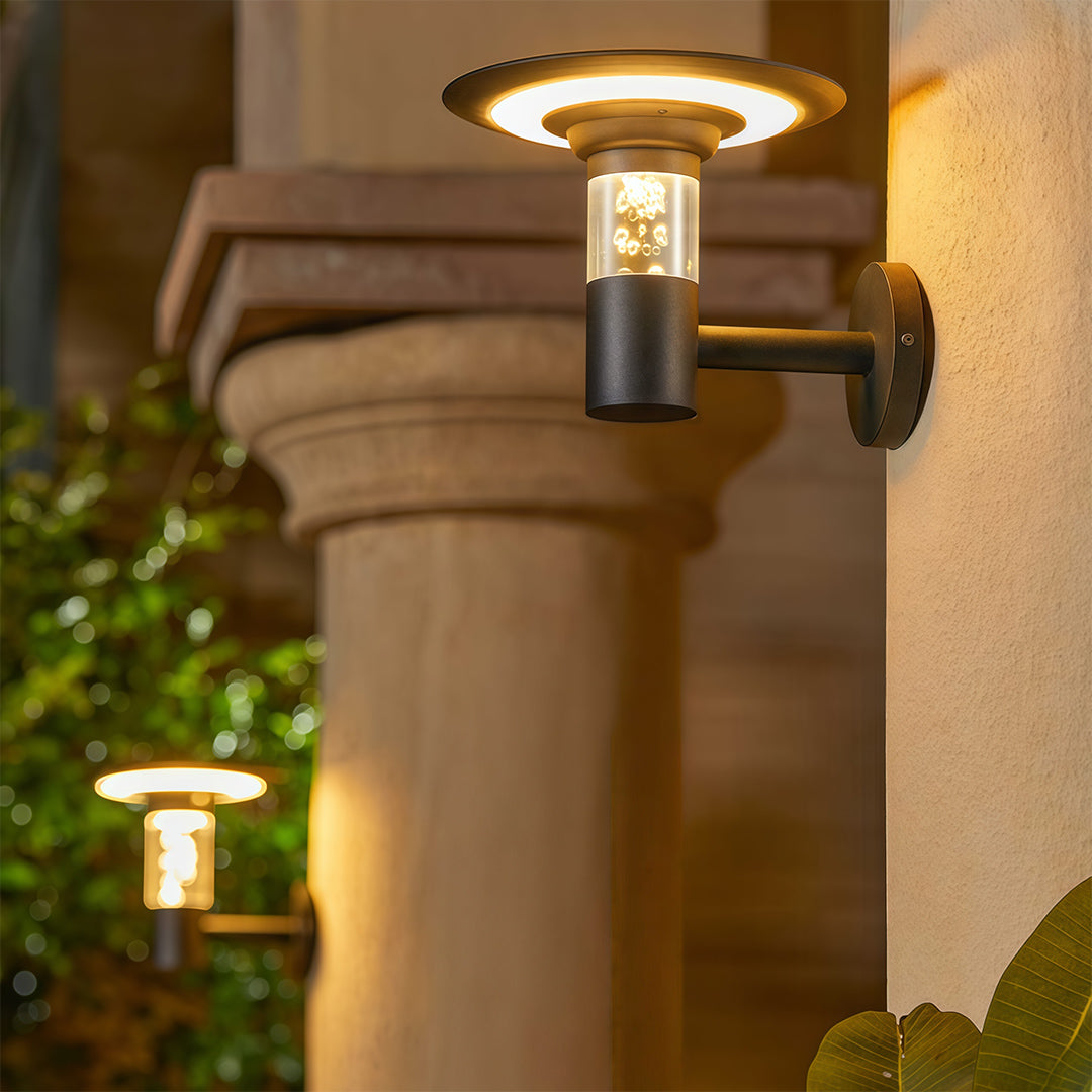Elegant solar outdoor wall lighting fixtures installed on classical columns, illuminating a patio at night.