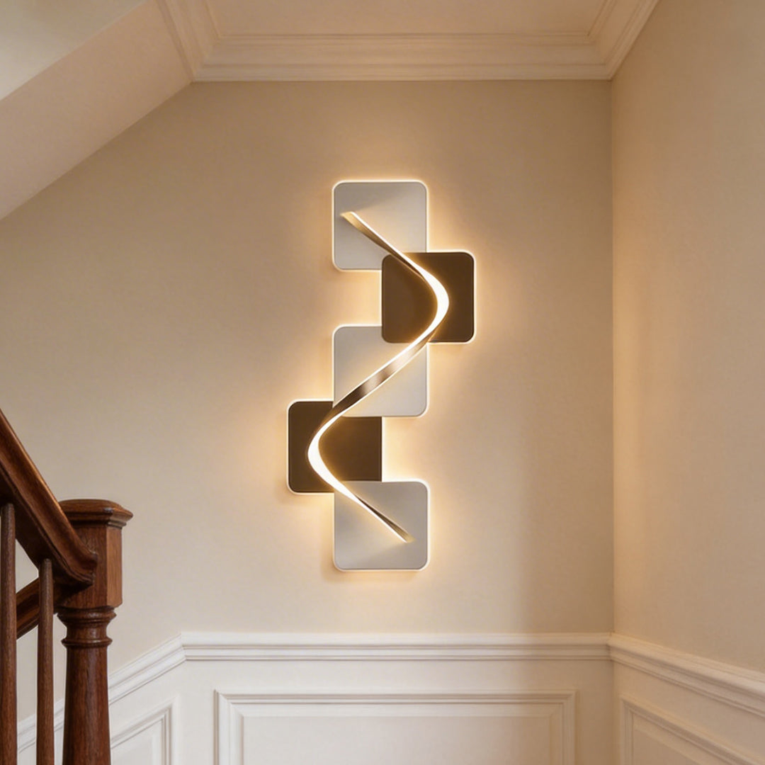 Elegant wave pattern wall sconce fixture glowing warmly on a beige home staircase landing wall.