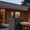 Exterior pillar lights illuminating a modern house entrance with wooden and stone accents at dusk.