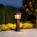 External post lights illuminating a garden pathway with lush greenery and paved stones.