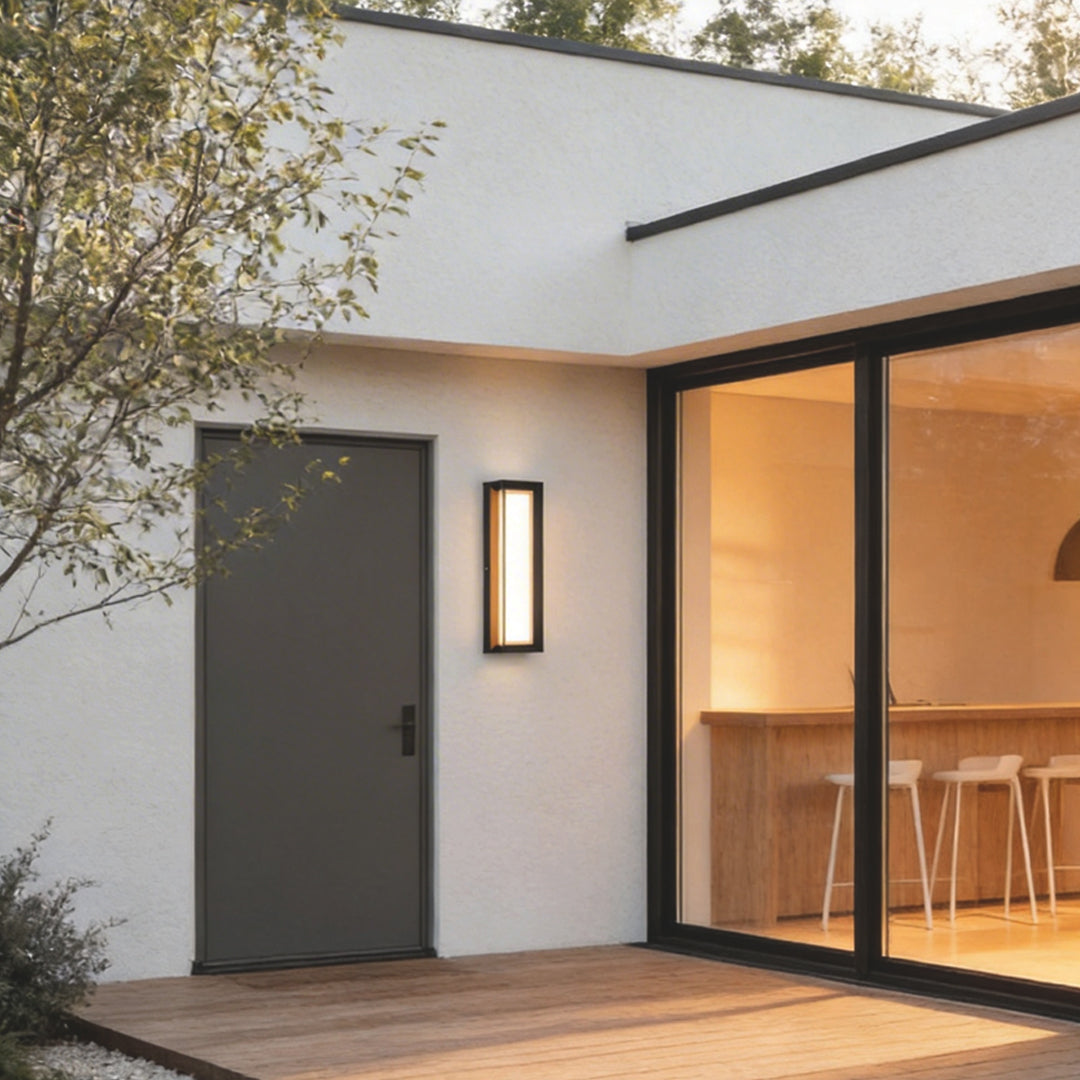 Fan shaped wall sconce with a modern design, illuminating a contemporary house entrance at night.