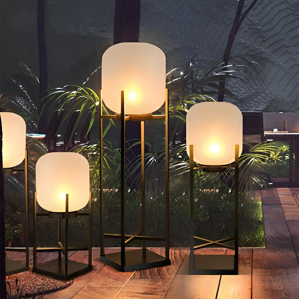 Outdoor standing light with frosted glass shade and black frame beside modern outdoor sofa.