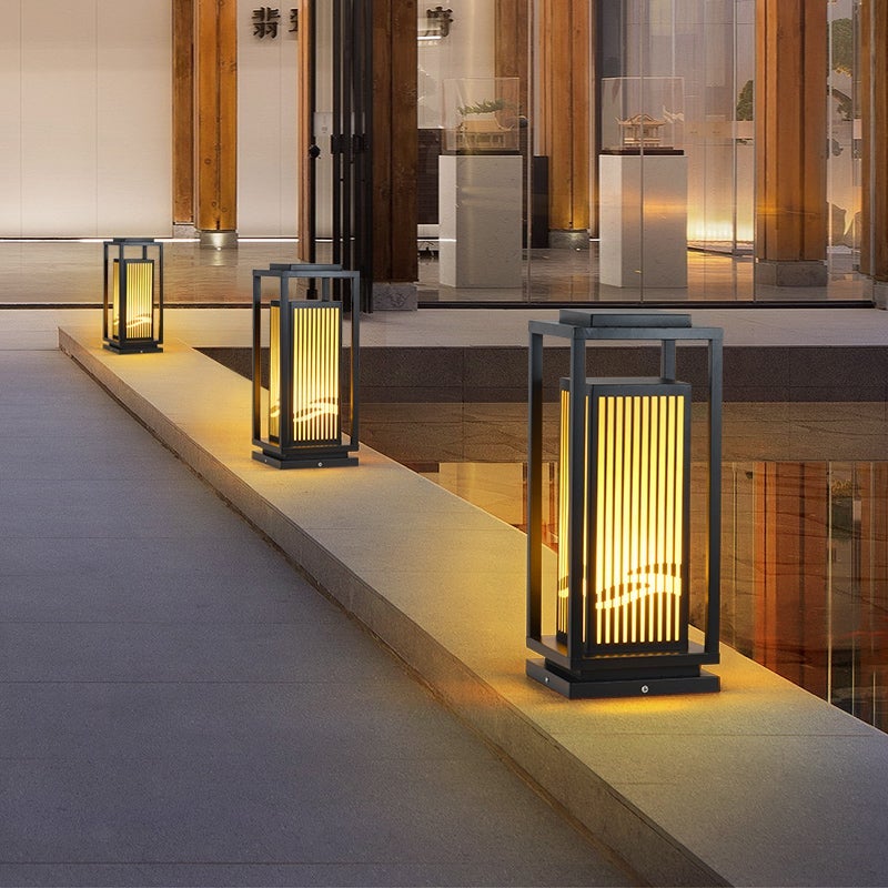 Garden bollards lights with a black finish, providing ambient light near a pond.