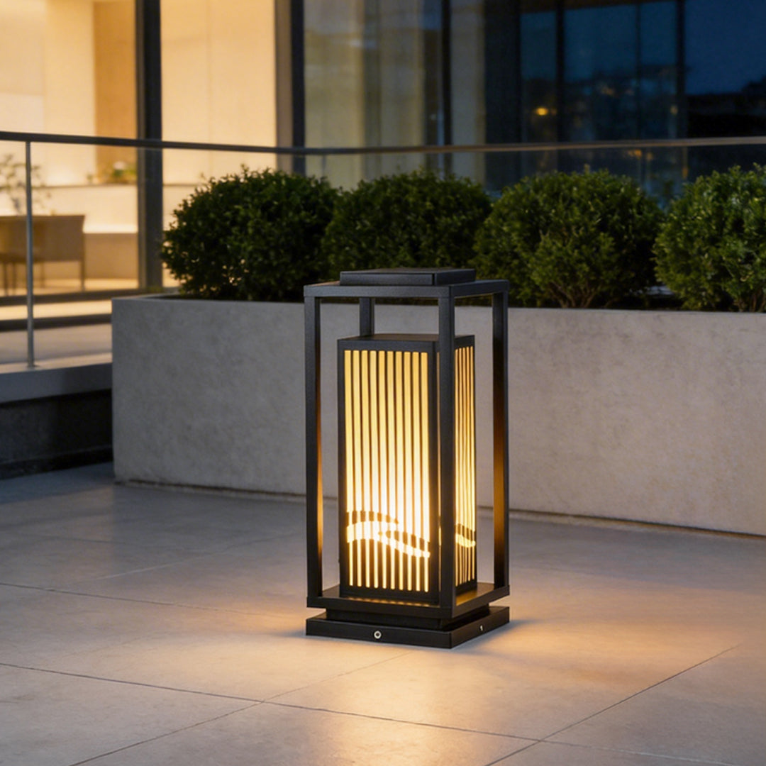 Garden bollards lights with a modern design, illuminating a pathway beside a building.