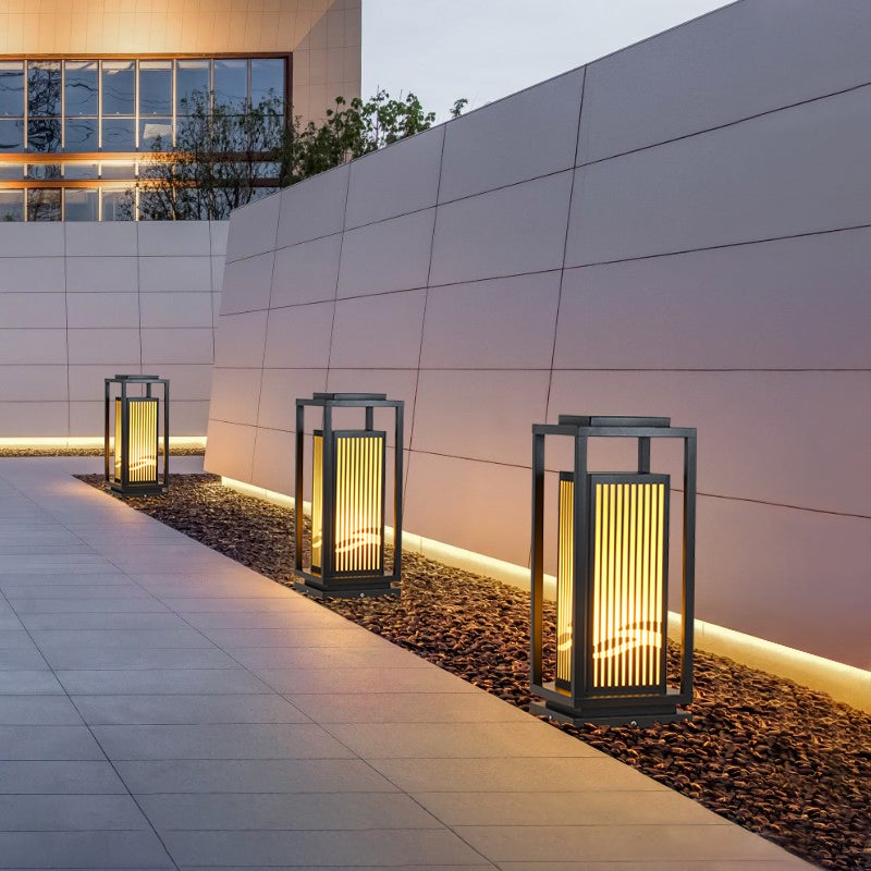 Garden bollards lights with a sleek black frame, providing warm light along a walkway.