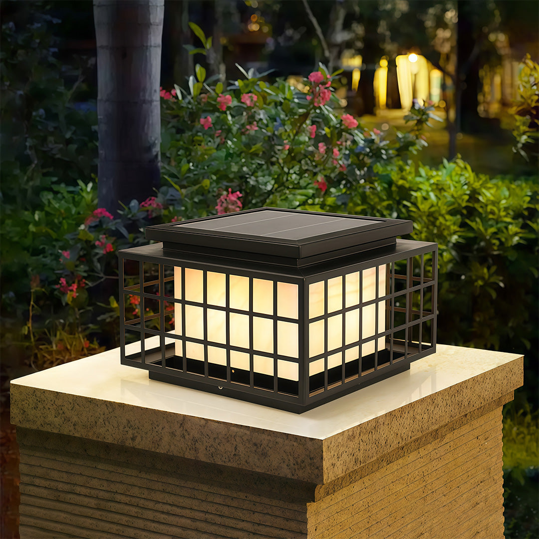 Modern gate pillar lights with a black finish, installed on a stone pillar near a garden entrance.