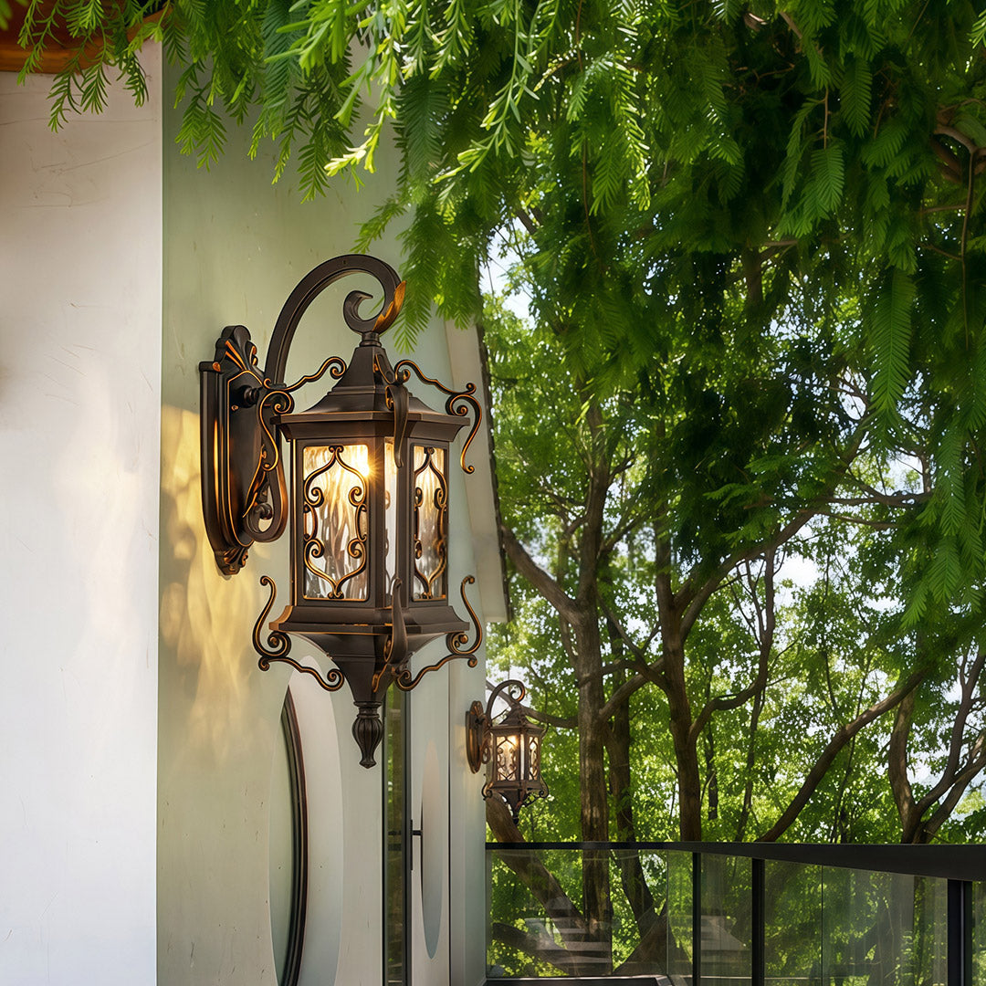 Outdoor wall sconce lights mounted on exterior wall under garden greenery.