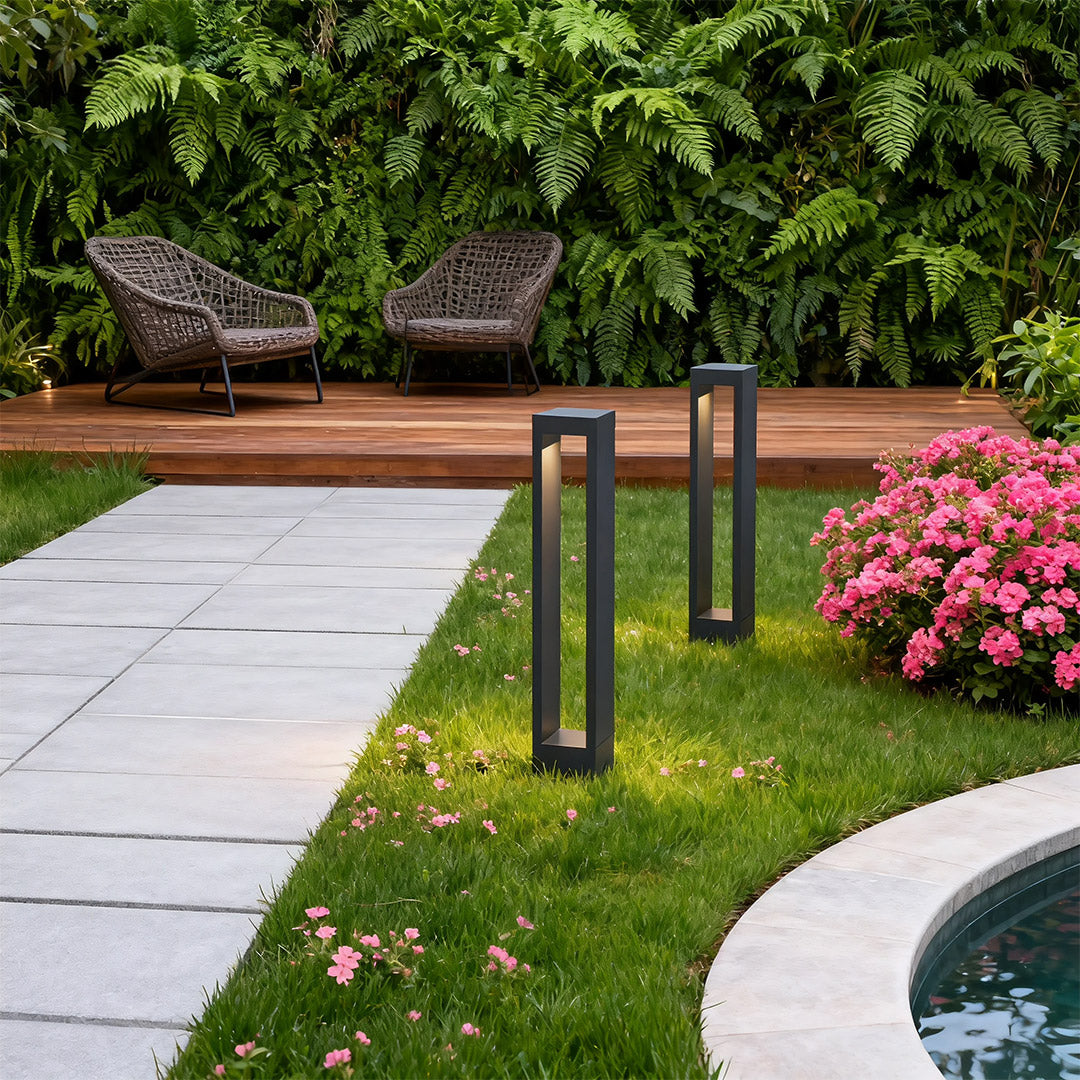 Garden pathway light near a garden with shrubs, adding a contemporary touch to the outdoor space.