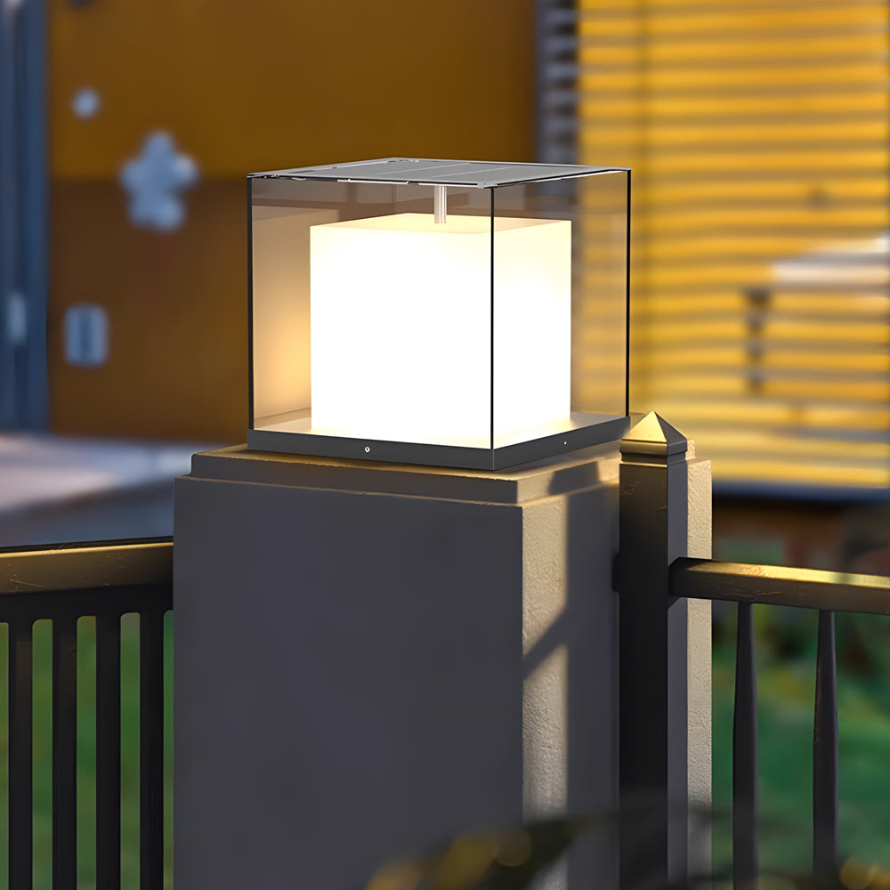 Gate pillar light featuring a minimalist cube shape, mounted on a concrete pillar near a wooden fence.