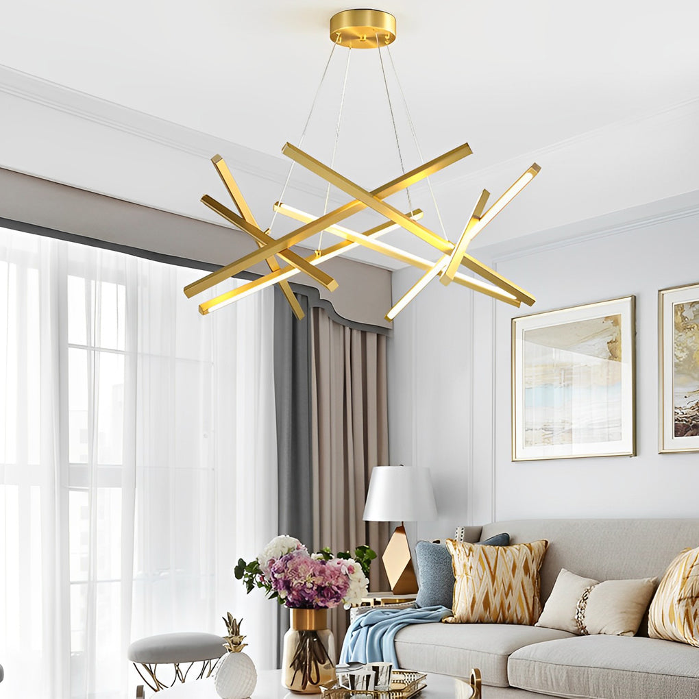 Geometric ceiling light with gold intersecting LED bars in a bright living room, acting as a sculptural centerpiece and light source.