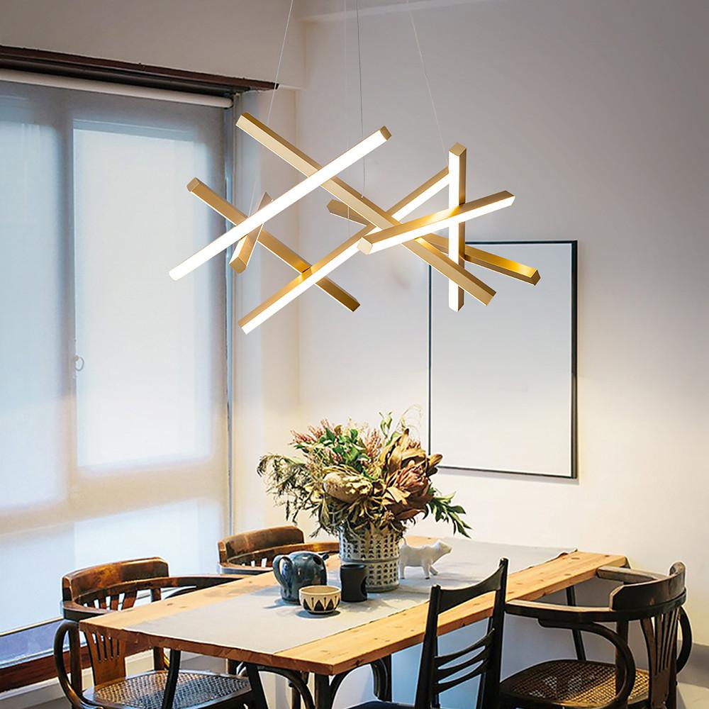 Geometric ceiling light combining gold and white LED bars above a dining table, delivering artistic form and balanced ambient lighting.