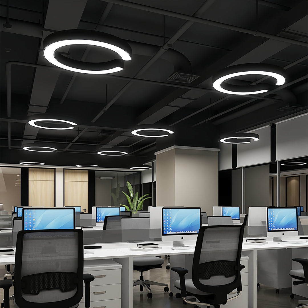 Multiple geometric pendant lights illuminating open office workspace with modern furnishings