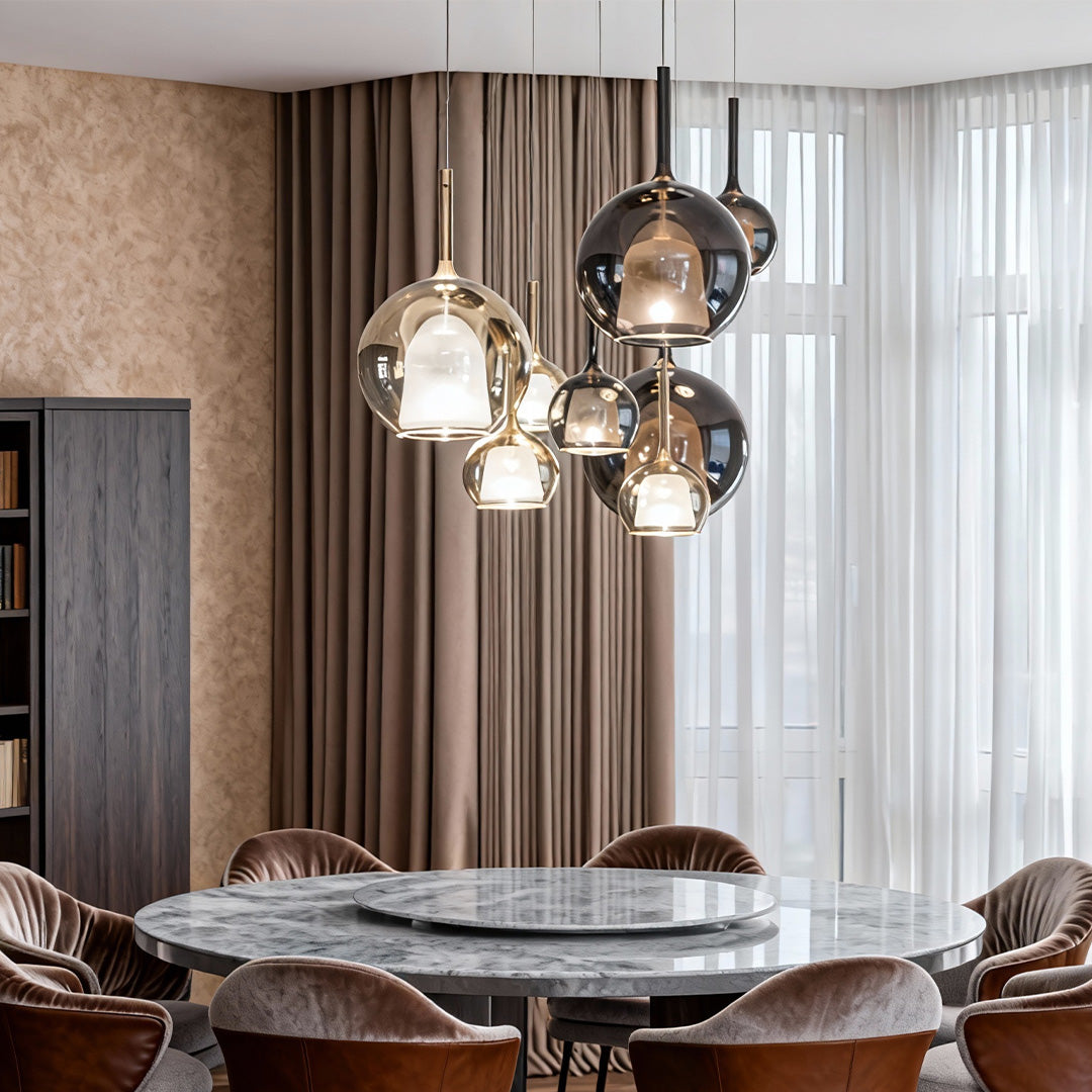Glass ball pendant light with a metallic finish, casting a soft glow in a stylish dining area.