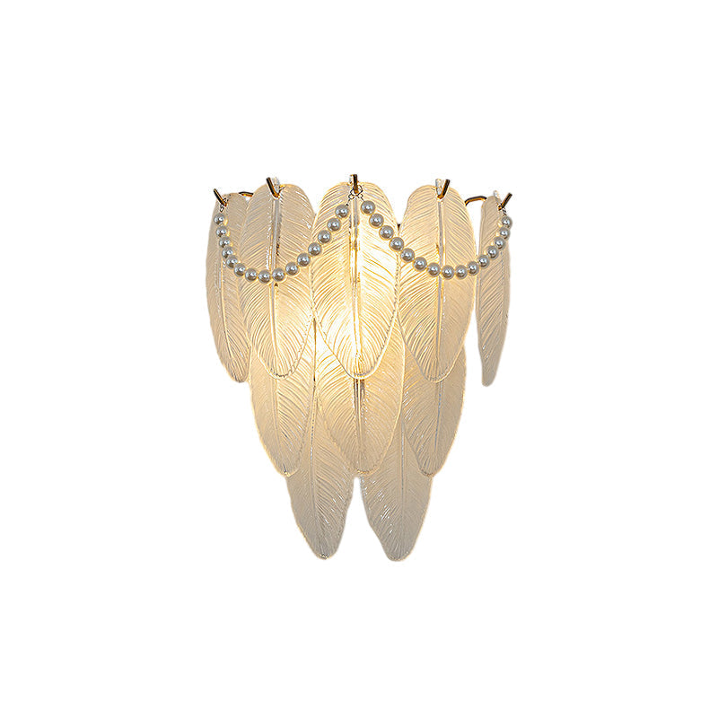 Glass feather wall light with a soft glow, adding elegance to a bedroom setting.