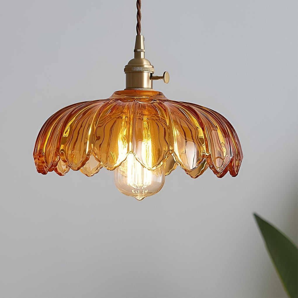 Amber glass pendant light featuring a textured scalloped shade and vintage-style brass socket with warm illumination.