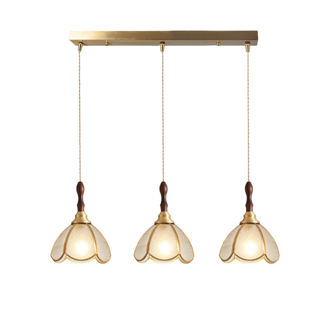 Three glass pendant lights with gold frames, illuminating a cozy dining area with floral glass shades.