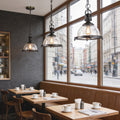 Glass pendant lights kitchen hanging above café-style tables creating a warm and inviting dining atmosphere.