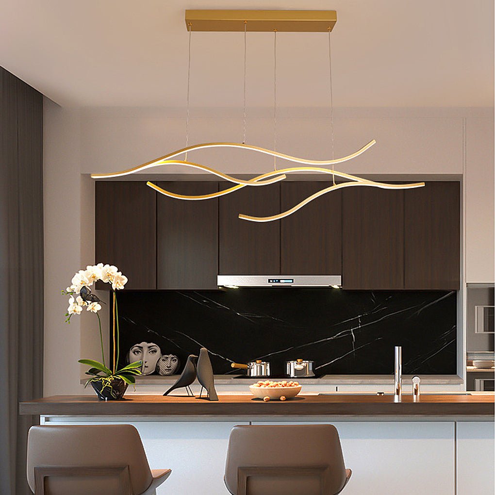 Flowing curved LED pendant light with gold finish above a modern kitchen counter.