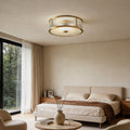 Gold drum ceiling light with a sleek design, providing warm illumination in a modern bedroom.