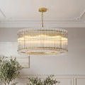 Luxurious gold drum-shaped glass lamp shade chandelier featuring vertical clear glass rods illuminating a sophisticated space.